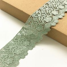 a roll of green lace sitting on top of a box next to a cardboard box