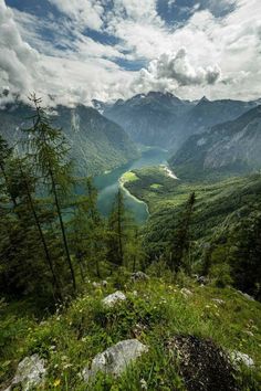 the valley is surrounded by green mountains and water, with clouds in the sky above