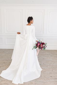 a woman in a white wedding dress holding a bouquet and looking off into the distance