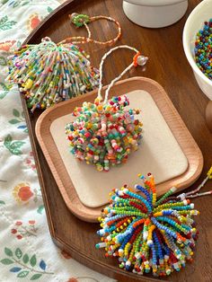 beaded ornaments are displayed on a wooden tray