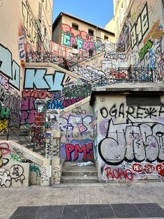 some graffiti on the side of a building and stairs in an alleyway with steps leading up to it