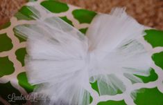 a present wrapped in green and white paper with a tulle bow on the top