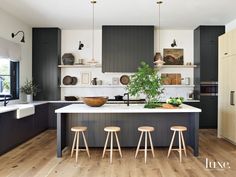 a kitchen with black cabinets and wooden stools next to an island in the middle