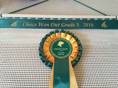 a close up of a ribbon on a table with a sign in the background that says once won out grade 5, 2016