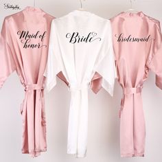 three bridesmaid robes hanging on a wall