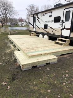 a camper trailer sitting on top of a wooden platform