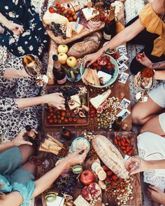 several people sitting around a table with food and drinks on it, all holding wine glasses