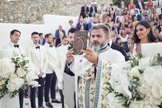 a man in a suit taking a picture with his cell phone at a wedding ceremony