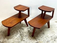 two wooden side tables sitting on top of a floor next to each other in front of a white wall