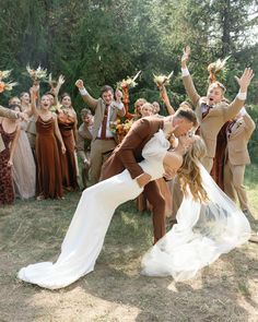 a bride and groom are kissing in front of their wedding party with hands up for the camera