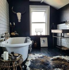 a bathroom with black walls and white tile flooring has a cowhide rug on the floor