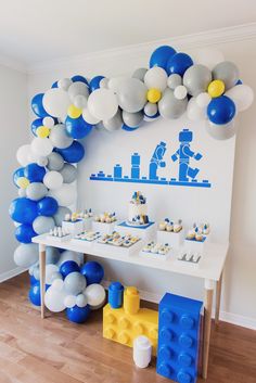 a birthday party with balloons and legos on the wall, including a cake table