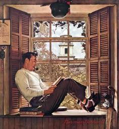 a man sitting on a window sill reading a book