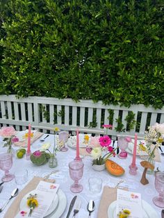 the table is set with pink and white flowers, plates, utensils and napkins