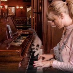 a woman is playing the piano with her cat