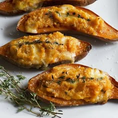 four baked sweet potatoes with cheese and herbs on a white plate, ready to be eaten