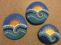 three painted rocks sitting on top of a table next to each other with water and sun in them