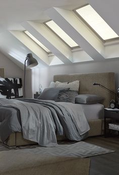 an attic bedroom with slanted ceiling and skylights above the bed, along with two lamps on either side of the bed