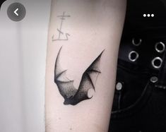 a black and white photo of a bat tattoo on the right arm, with an anchor in the background