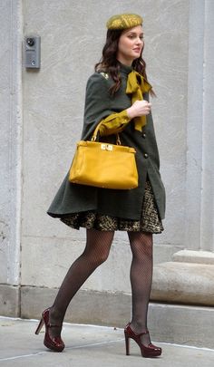 a woman is walking down the street carrying a yellow handbag and wearing tights