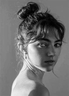 a black and white photo of a woman's face with her hair in a bun