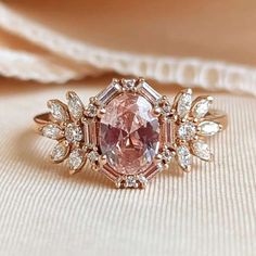 a pink diamond ring sitting on top of a white cloth