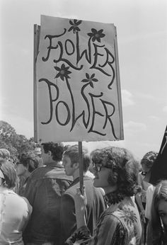 black and white photograph of people holding a sign that says flower power on the front