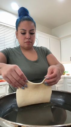 a woman is kneading dough in a skillet