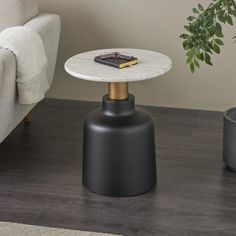 a small table with a book on it next to a couch and potted plant