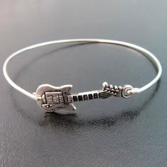 "Guitar Bracelet - Country Music Jewelry - Rock Music Jewelry A silver tone guitar charm has been transformed into a silver guitar bangle bracelet with a silver filled band. This silver guitar Jewelry is the perfect gift for music lover, gift for music teacher, or musician gift. I can also make this guitar bangle bracelet with a sterling silver band for an additional $10. If you would like this option for your country jewelry or rocker jewelry select from options when ordering. This silver guita Rocker Chic Jewelry, Lover Guitar, Guitar Bracelet, Rocker Jewelry, Guitar Jewelry, Music Bracelet, Guitar Lover, Guitarist Gifts, Jewelry Bangles