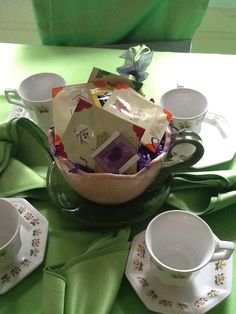 tea cups and saucers on a green table cloth with napkins in the middle