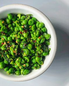 a white bowl filled with green peas on top of a table