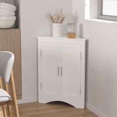 a white cabinet sitting in the corner of a room next to a table and chairs