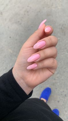 a woman's hand with pink nail polish on it and blue shoes in the background