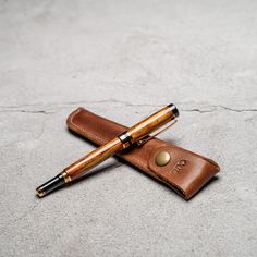 two pens sitting on top of a leather case