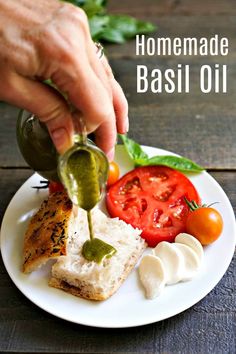 homemade basil oil being drizzled on bread with tomatoes and mozzarella