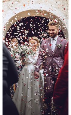 a bride and groom are walking through confetti