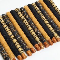 there are many black and gold colored sticks lined up on the white surface, each with different toppings