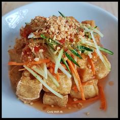 a white plate topped with tofu and veggies covered in grated cheese