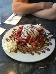 a waffle topped with strawberries and drizzled chocolate on a white plate