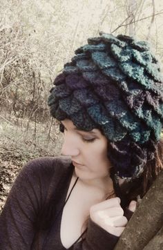 a woman wearing a knitted hat standing next to a tree