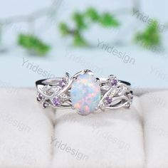 a white opal and pink sapphire ring on top of a cushion - like surface