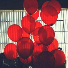 a bunch of red balloons floating in the air