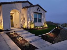 a house that is lit up at night with lights on the front door and steps leading to it