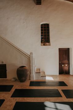 an empty room with black and white tiles on the floor, two large vases next to it