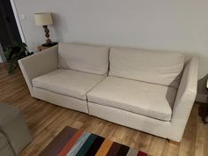 a white couch sitting on top of a hard wood floor next to a table and lamp