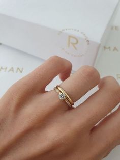 a woman's hand with a ring on it and a box in the background