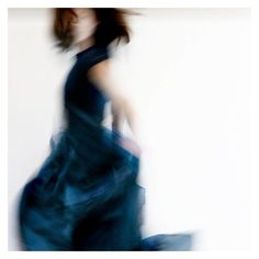 a blurry photo of a woman in a blue dress with her hand on her hip