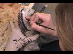 a woman is working on an art project with clay and paintbrushes in her hands