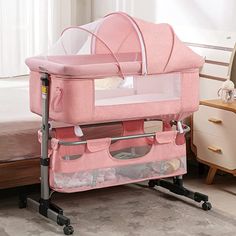 a pink baby crib sitting on top of a bed next to a night stand